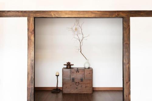 a room with white walls and a table with a vase at Hyuhyudang in Gyeongju
