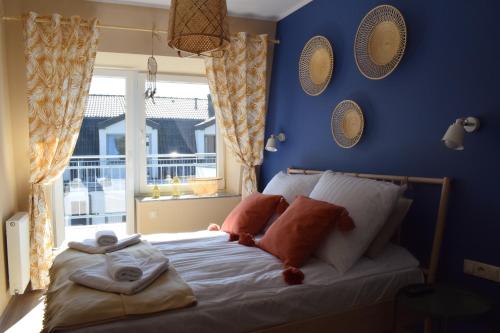 a bedroom with a bed with blue walls and a window at Apartament Silence Baltic Boho in Pobierowo