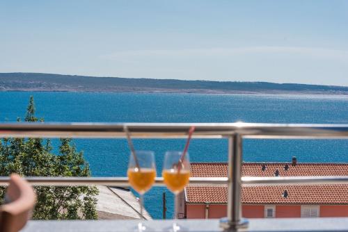 two wine glasses on a balcony overlooking the water at Apartmani Jadranka in Starigrad-Paklenica