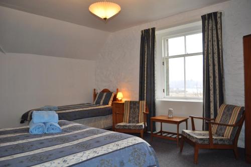 Habitación de hotel con cama, sillas y ventana en Auchmore Apartments, en Killin