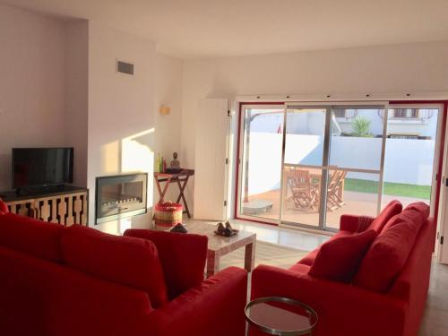 uma sala de estar com um sofá vermelho e uma televisão em Casa Oliveiras em Comporta