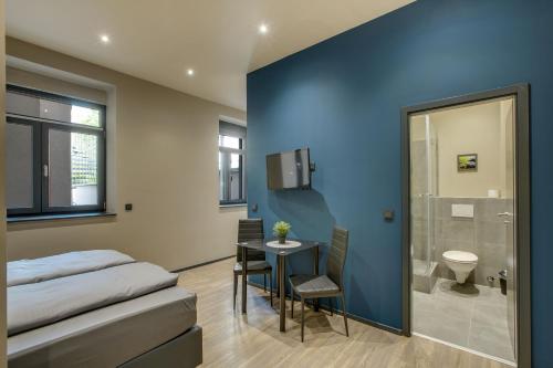 a bedroom with a bed and a table and a bathroom at Liro Stadt Apartments in Krefeld