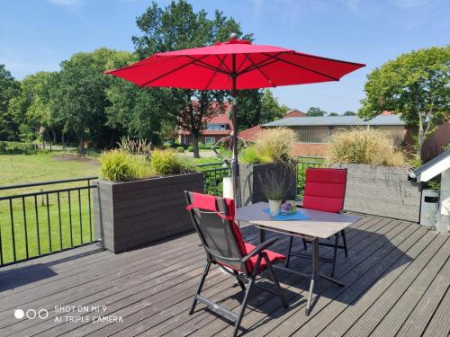 a table with two chairs and a red umbrella on a deck at LANDLOFT am Paradies in Westerstede