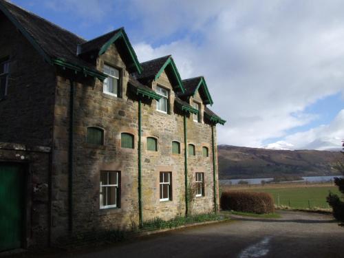 an old stone building with a roof at Auchmore Apartments in Killin