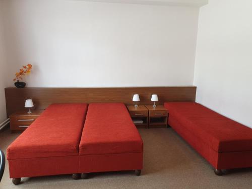 een slaapkamer met 2 rode bedden en 2 tafels bij U Matěje in Luhačovice