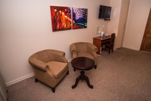 a room with two chairs and a table and a desk at Adelante Lodge in Bloemfontein