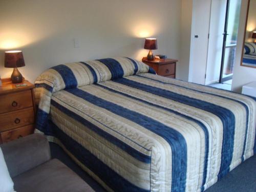 a bedroom with a bed with a blue and white striped blanket at Warkworth Country House in Warkworth