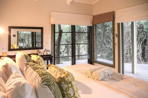 ein Wohnzimmer mit einem Bett und großen Fenstern in der Unterkunft Khangela Private Game Lodge - Self Catering - Bedrooms are 3 Separate Chalets - Hluhluwe in Hluhluwe