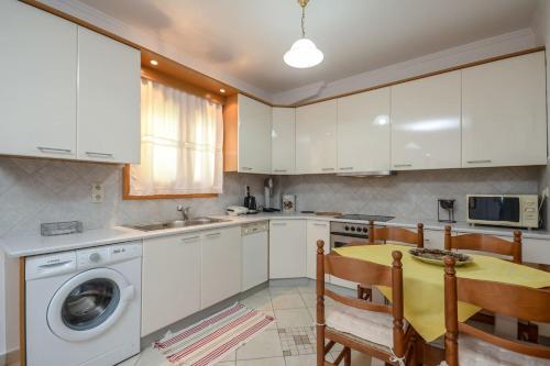 uma cozinha com armários brancos, uma mesa e uma máquina de lavar roupa em Independent AGAPITOS APART , 2BDRM, private patio em Naxos Chora