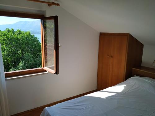 a bedroom with a bed and a window at Apartments Duka in Lumbarda