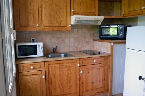uma cozinha com armários de madeira, um lavatório e um micro-ondas em Studio à 100 mètres des thermes vue sur montagne. em Amélie-les-Bains-Palalda