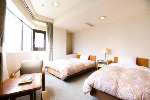 a hotel room with two beds and a table and a chair at Hotel Ohedo in Tokyo