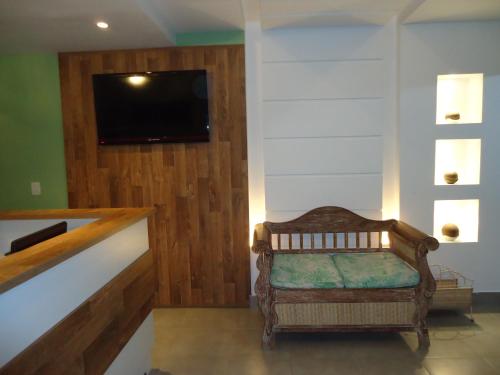 a living room with a chair and a tv on a wall at Hospedagem Belo Horizonte in Macaé