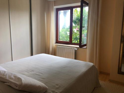 a bedroom with a white bed and a window at Palm Garden Apartment in Kastav
