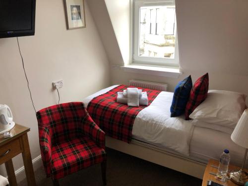 um pequeno quarto com uma cama e uma cadeira em Montague Guest House em St. Andrews