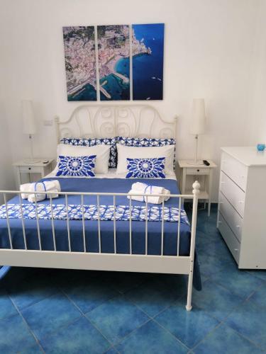 ein Schlafzimmer mit einem weißen Bett und blauen und weißen Kissen in der Unterkunft Velia34 in Salerno