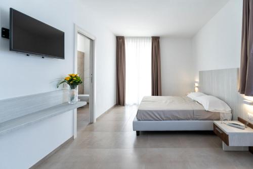 Vasto Aparthotel في فاستو: غرفة نوم بسرير وتلفزيون على جدار