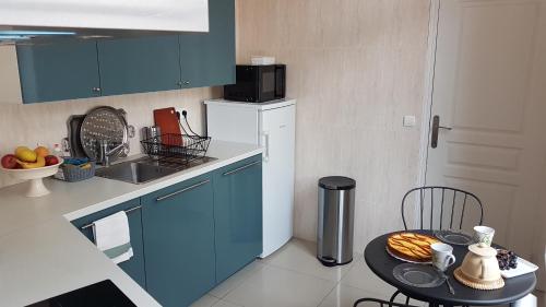 une cuisine avec des placards bleus et une table avec de la nourriture. dans l'établissement Appartement Cosy et Lumineux idéalement placé, à Boulogne-sur-Mer