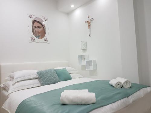 a white bedroom with a bed with towels on it at Gloria Apartments 2 in Međugorje