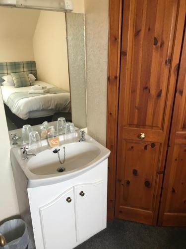 a bathroom with a sink and a mirror and a bed at Garfield Guesthouse in Dingwall