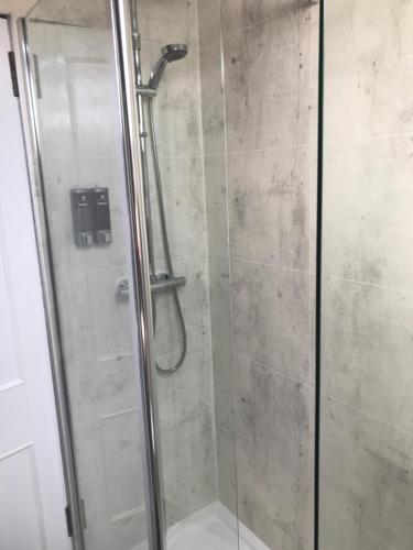 a shower stall with a glass door with a shower at Garfield Guesthouse in Dingwall