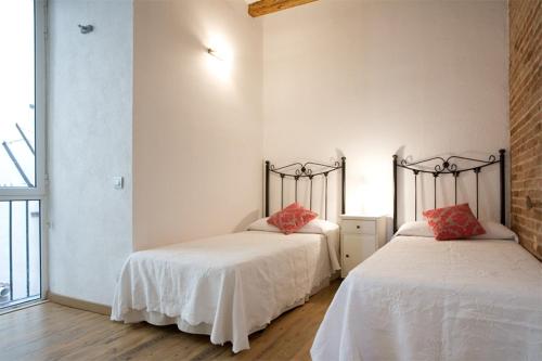 1 Schlafzimmer mit 2 Betten mit weißer Bettwäsche und roten Kissen in der Unterkunft OLYMPIC VILLAGE in Barcelona