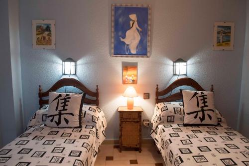 a bedroom with two beds and a nightstand with two lamps at CULTURAS Y COLORES EN ALMAGRO -WIFI alta velocidad, NETFLIX, Parking -Promocion EMPRESAS- in Almagro