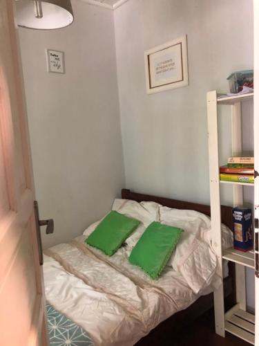 a small bedroom with a bed with two green pillows at Domek Bogaczewo in Bogaczewo