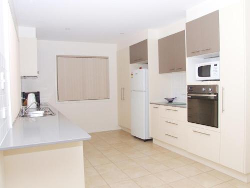 a kitchen with white cabinets and a white refrigerator at Parker by the Sea in Batemans Bay