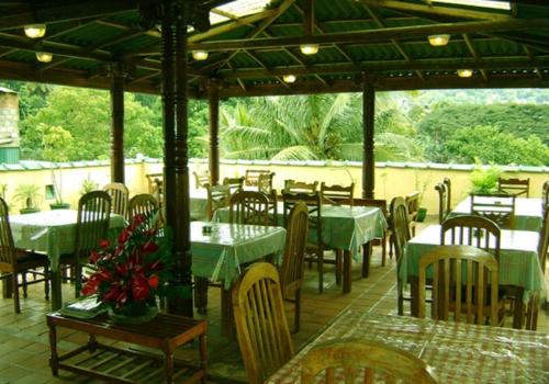 a restaurant with green tables and chairs and tablesearcher at Palm Garden Home Stay in Kandy