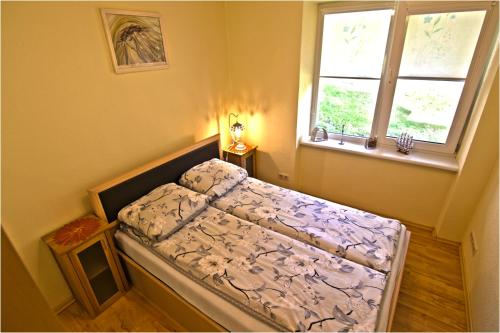 een kleine slaapkamer met een bed en 2 ramen bij Nida Amber in Nida