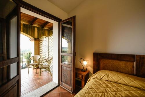 a bedroom with a bed and a door to a balcony at Hotel Funtana Ena in Loceri