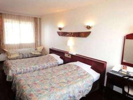 ein Hotelzimmer mit 2 Betten und einem Spiegel in der Unterkunft Amami Resort Bashayamamura in Amami