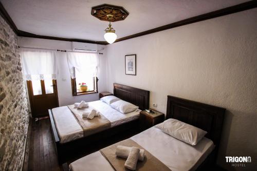 a bedroom with two beds and a window at Trigona Guest House & Hostel in Gjirokastër