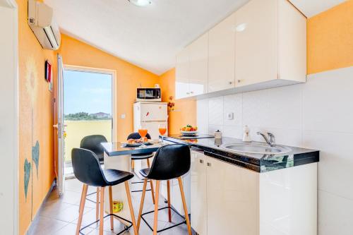 Una cocina con tres taburetes de bar y un fregadero. en Apartments Petra, en Trogir