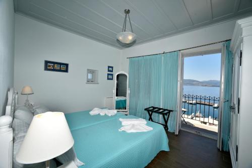 a bedroom with a blue bed with a view of the water at Heliades Maisonettes in Mithymna