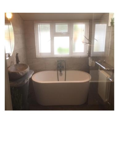 a bathroom with a tub and a sink and a window at Bambu Cottage in Newquay