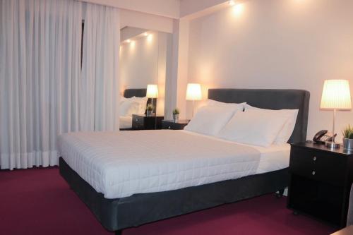 a bedroom with a large bed with white sheets and pillows at Hotel Victory in Athens