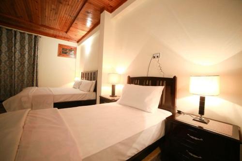 een slaapkamer met 2 bedden en een lamp en 2 bedden bij Chinar Resorts in Bāla Pīr Ziārat