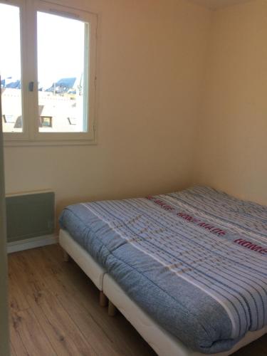 un lit dans une chambre avec une fenêtre dans l'établissement Cabourg T2 proche plage, à Cabourg