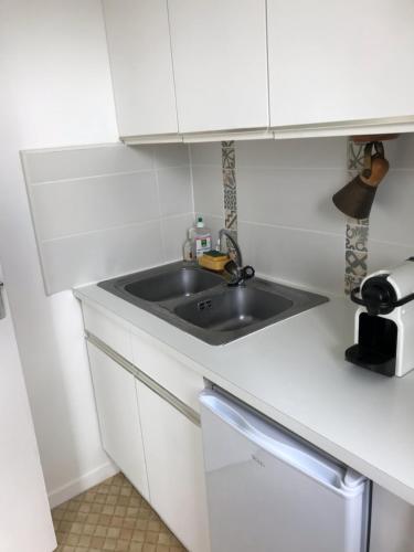 - une cuisine avec un évier et des placards blancs dans l'établissement Cabourg T2 proche plage, à Cabourg