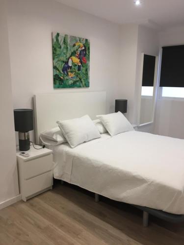 - une chambre avec un lit blanc et une peinture murale dans l'établissement Garden Turia Downtown, à Valence
