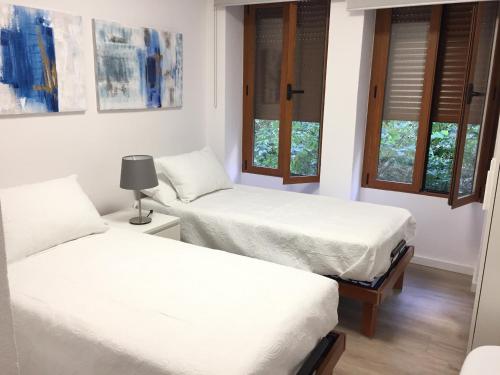 two beds in a room with two windows at Garden Turia Downtown in Valencia