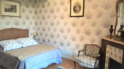 a bedroom with a bed and a chair at Château de la Vernède, la Grande Vernède in Saint-Rémy-de-Chargnat