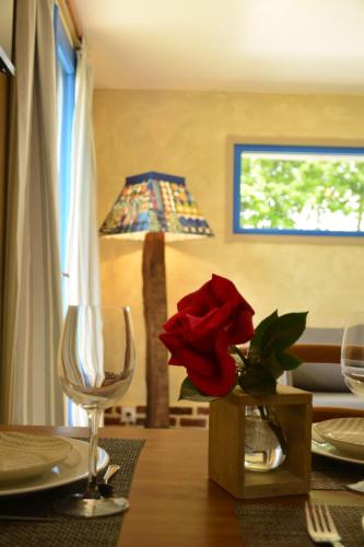 une table avec une rose rouge dans un vase sur une table avec une lampe dans l'établissement GITE 