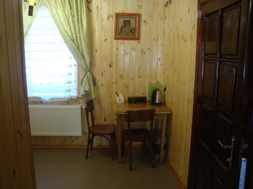 een kamer met een houten tafel en stoelen en een raam bij Сердце Каньона in Kamjanets-Podilsky