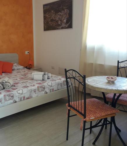 a bedroom with a bed and a table and chairs at Affittacamere Il FIORE in Posada