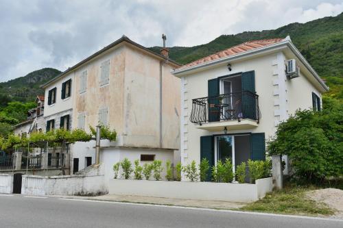 a white house with green shutters on a street at Hajdi in Kamenari