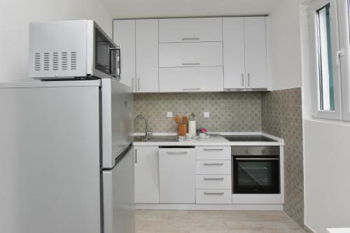a kitchen with white cabinets and a stainless steel refrigerator at Hajdi in Kamenari