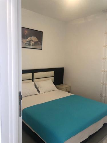 a bedroom with a bed with a blue blanket at Apartmani Dini in Ulcinj